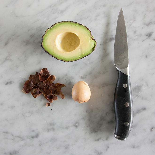 Schälen eines Avocadokerns mit einem Messer, von Botanopia