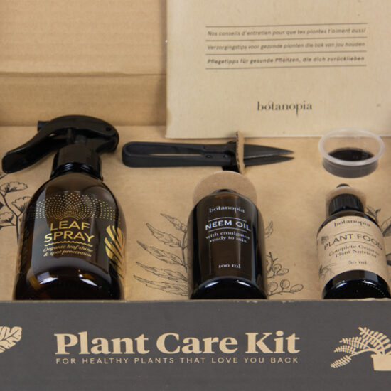 Plant care kit open box close up of the product glass bottle, neem oil, plant food, measuring cup, bonsai scissors and plant care tips book