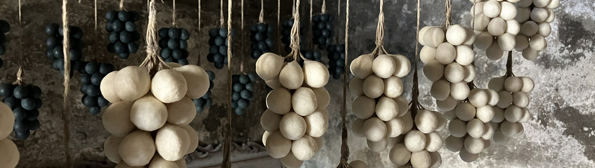 banner bunches of white grape soaps hang on a wire drying in the sun in lebanese family workshop