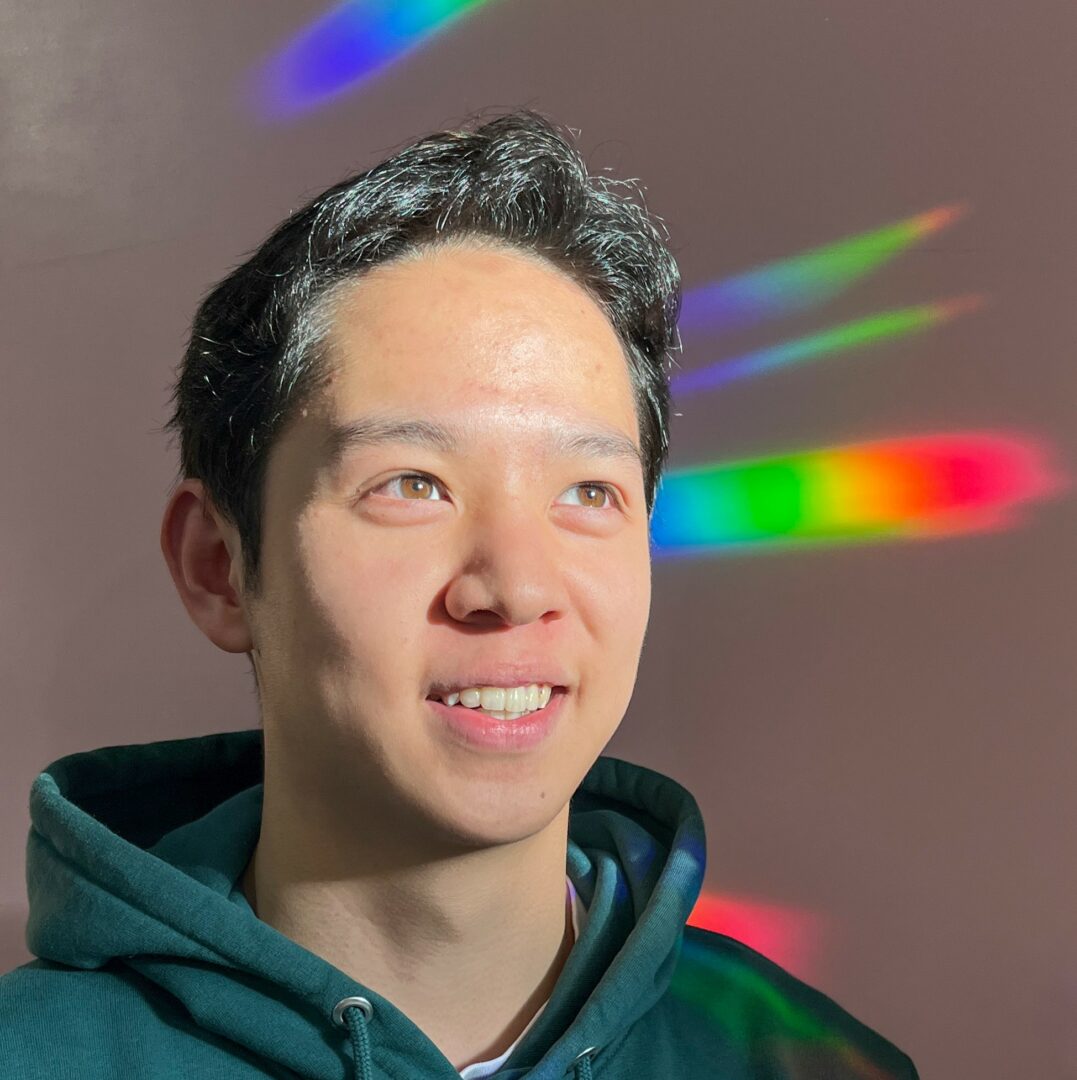 person in front of a window with behind on the wall, rainbow from the sticker