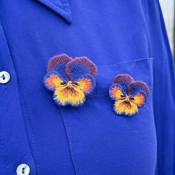 Pansies embroidered brooches on blue blouse