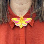 Rosy Maple moth embroidered brooch on red blouse
