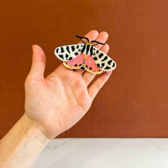 Tiger moth embroidered brooch holding in hand