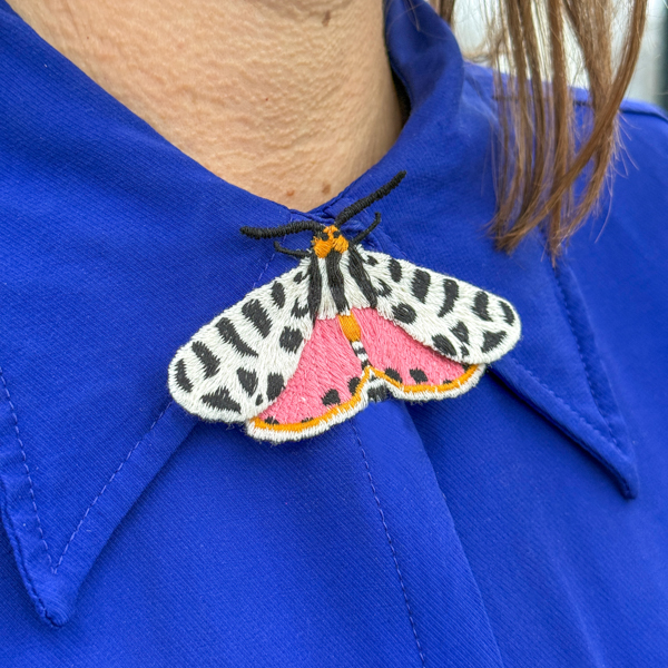Tiger moth embroidered brooch on blue blouse